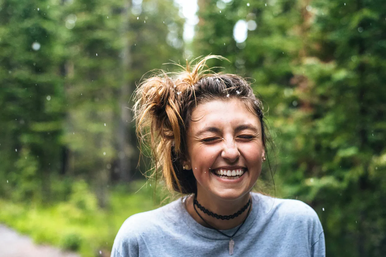 A young person laughing outdoors among trees